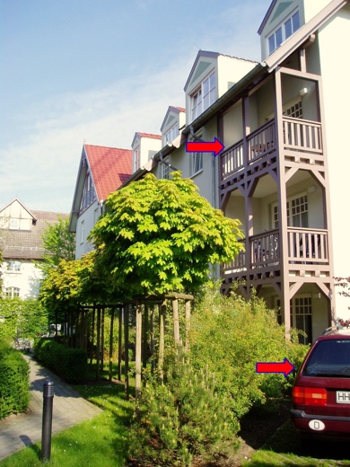 Der Parkplatz befindet sich direkt unter der Wohnung im zweiten Stock, die über einen mit Holz ausgekleideten Balkon verfügt.